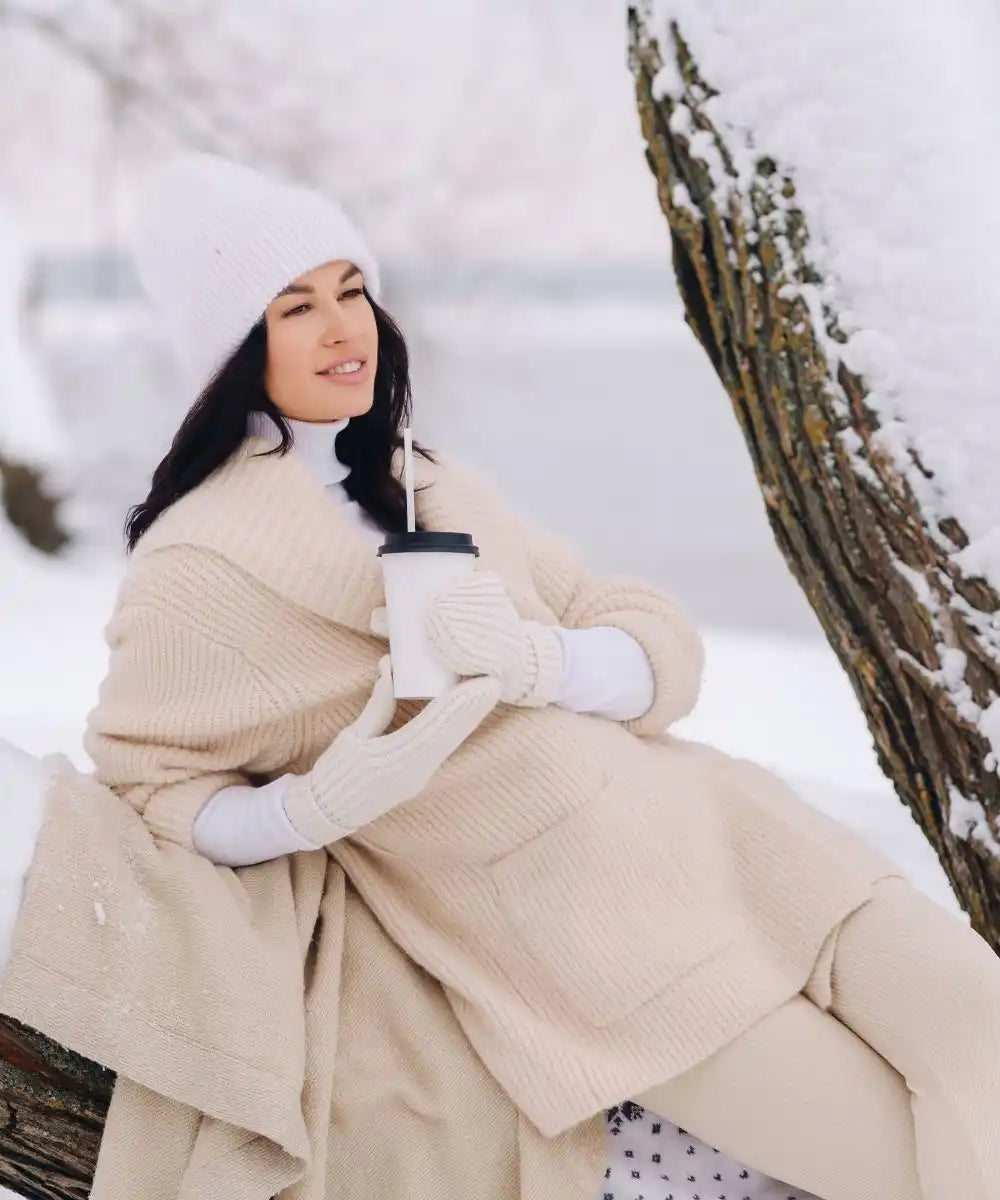 Femme en vêtements d'hiver tenant une tasse de café.